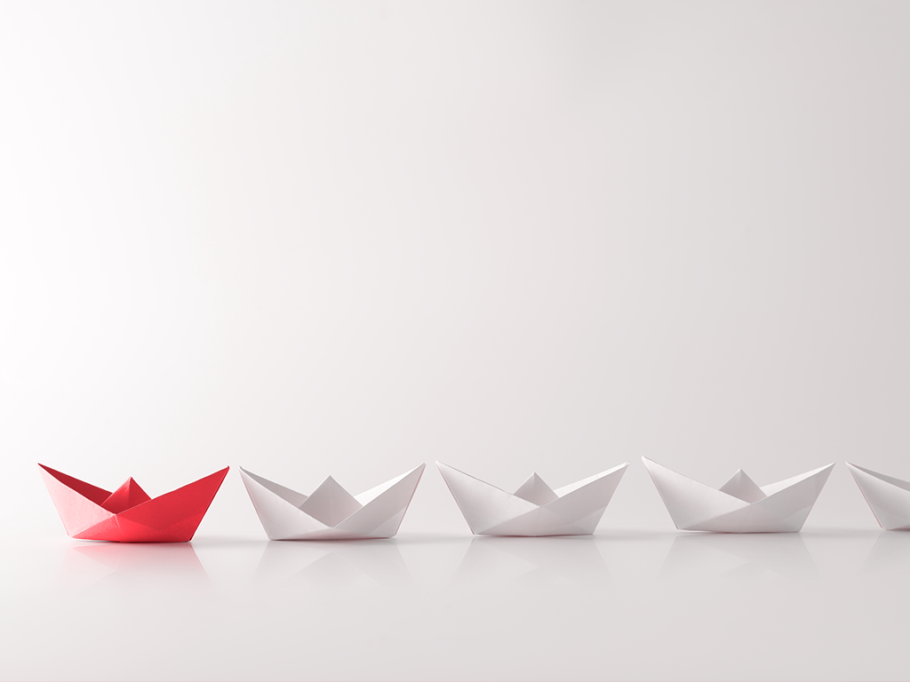 Leadership concept with red paper ship leading among white