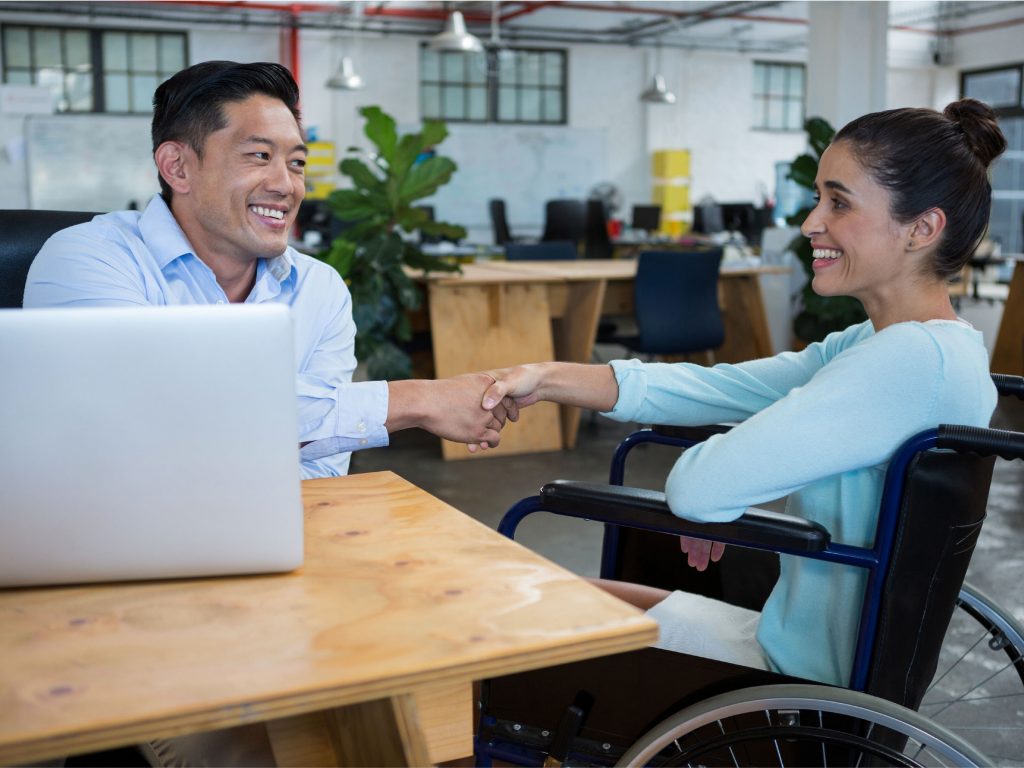 Businessman shaking hands with specially-abled colleague stock photo