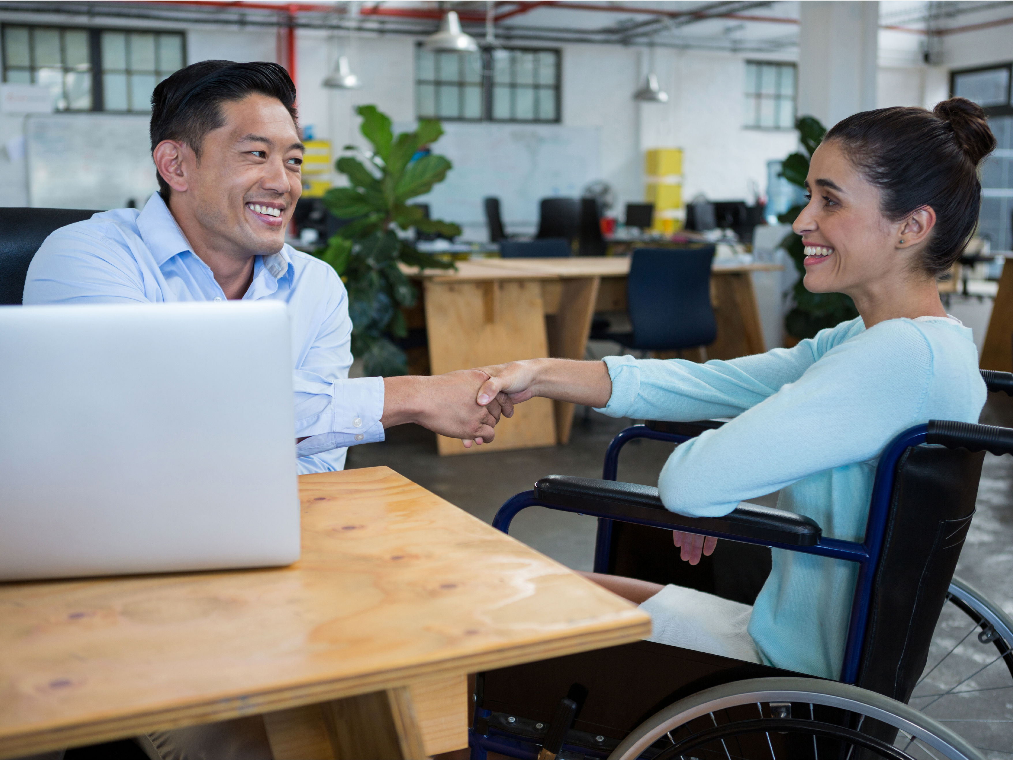 Businessman shaking hands with specially-abled colleague stock photo